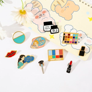 Detail shot of creative makeup-themed enamel pins including lipstick and eyeshadow designs