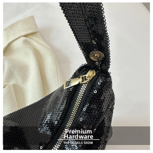Détails des paillettes noires scintillantes et du zip en métal doré clair sur le sac