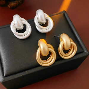 Close-up of matte gold and silver geometric multi-hoop earrings in a black jewelry box