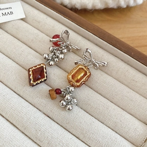 Close-up of asymmetric bow earrings with vintage red beads and amber gems in a display box