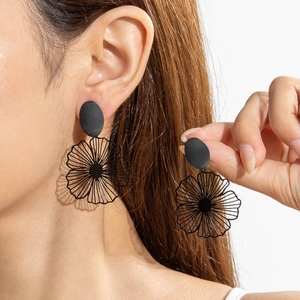 Détail de boucles d'oreilles fleurs noir mat avec design de pétales ajourés