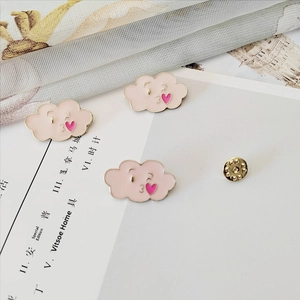Close-up of pink cloud enamel brooch with heart detail and butterfly clasp on fabric