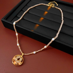 Detail of a vintage pearl necklace with an orange opal pendant on black velvet