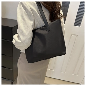 Black nylon tote bag styled with a beige blazer for a professional commuting look