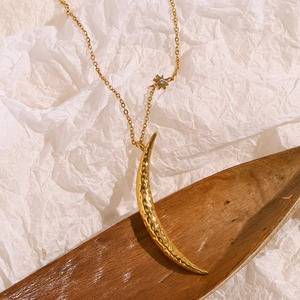 Detail of 18K gold crescent pendant with hammered texture and star accent on fine chain