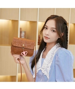 Close-up of brown PU crossbody bag featuring heart charm and cute embossed patterns