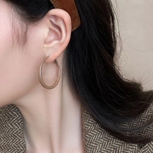 Close-up of minimalist khaki round hoop earrings worn by a model for a stylish look