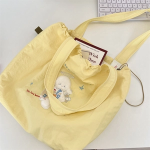 Detail of embroidered angel on yellow canvas tote bag with drawstring closure