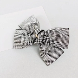 Macro detail of a silver sparkling rhinestone bow clip on a classic white background