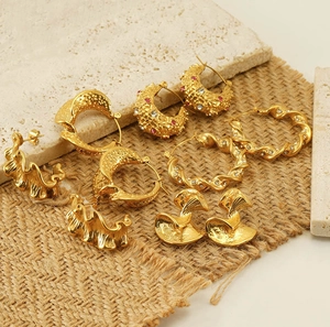 Close-up of vintage 18k gold plated hoop earrings on textured travertine and jute stone