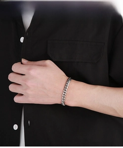 Close-up of a silver-tone Cuban link bracelet featuring mixed polished and sandblasted finishes