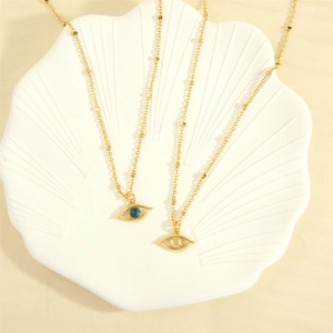 Detailed shot of two 18K gold plated evil eye necklaces on a white shell plate