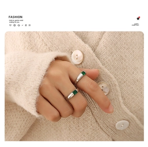 Close-up of elegant silver titanium rings with emerald green zircon on a model's hand