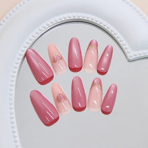 Handmade pink cat eye press-on nails with 3D gold hearts and French tip design