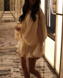 Detail view of beige puff sleeve chiffon dress with ruffle layers and pleated design
