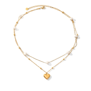 Macro detail of a double-layer gold necklace featuring a pearl and heart pendant