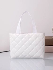 Close-up of white quilted leather tote bag with dual handles on a reflective surface
