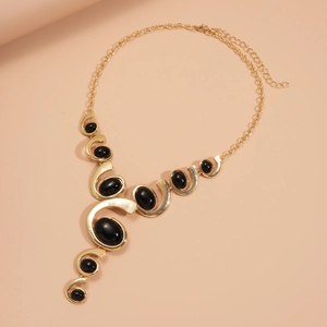 Détail macro du collier spirale ovale doré avec incrustations de résine noire