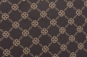 Macro shot of brown leather texture with golden geometric chain and clover patterns