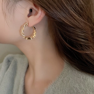 Detail of model wearing a gold geometric C-shaped earring with zircon paving and smooth metal