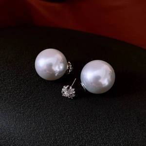 Detail of floral silver stud earrings with pearls and crystals on a black background