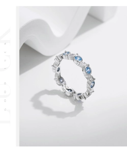 Macro shot of silver eternity ring with blue and white round-cut sparkling gemstones