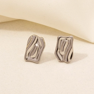 Macro shot of silver bow-shaped geometric earrings on elegant fabric backdrop