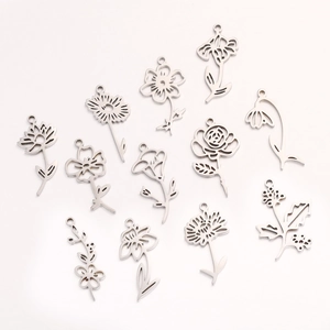 Twelve silver stainless steel birth flower pendants with intricate cutout designs on white background