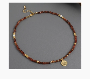 Close-up of beaded necklace with freshwater pearls and gold evil eye coin pendant