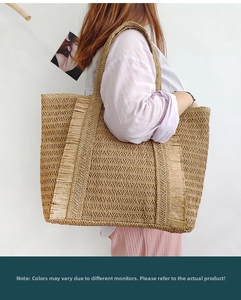 Side view of a large straw tote bag with fringe details and natural woven texture
