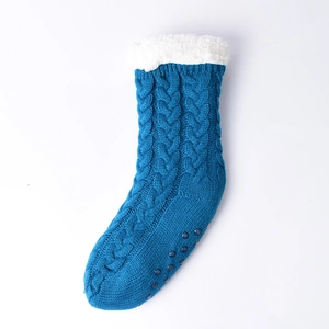 Detail of blue knit slipper sock with white plush cuff and non-slip sole grip pattern