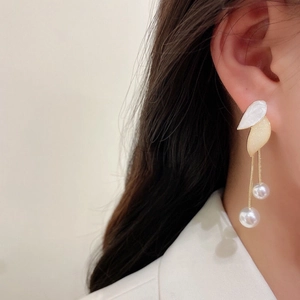 Detailed close-up of long tassel earrings with pearl leaf design on a model