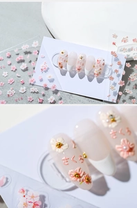 Macro detail of cherry blossom nail stickers with pink flowers and 3D gold pearl accents