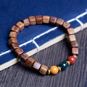 Detail of sandalwood bead bracelet featuring dark square beads and colorful spacer rings