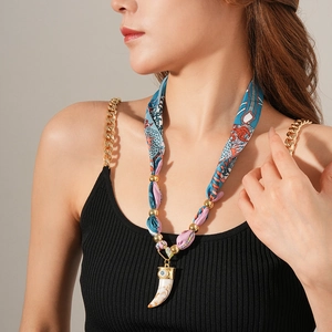 Dettaglio della collana boho con pendente a elefante, tessuto a motivi e perline d'oro