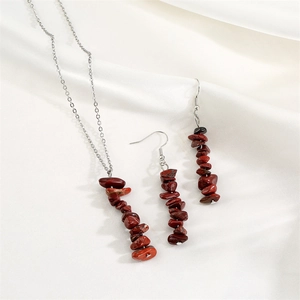 Detailed view of red jasper chip stone tassel necklace and earrings set on white silk