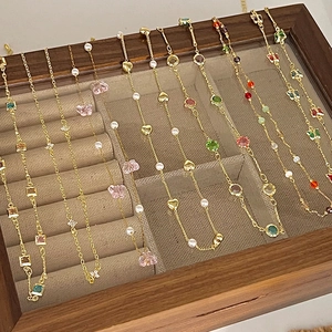 Elegant gold necklaces with colorful cubic zirconia pendants in a premium wooden box