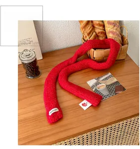 Detail of red knit scarf with white VEGETABLE letter tag on a cozy wooden table background
