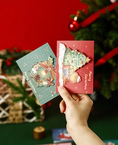 Close-up of 3D pop-up Christmas cards in classic red and dark green with gold lettering