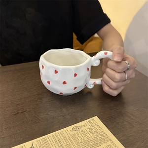 Macro detail of French retro handmade ceramic mug with red hearts and vintage handle