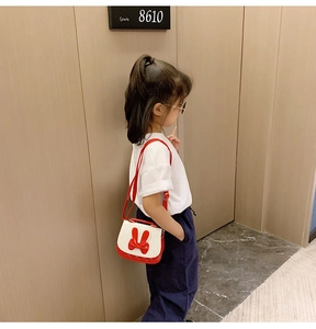 Close-up of a girl wearing a red and white crossbody bag with a large decorative bow