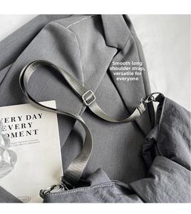 Detail of adjustable nylon strap and silver metal buckle on a grey crossbody bag
