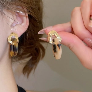 Close-up of geometric leopard acetate resin drop earrings with golden hammered metal texture