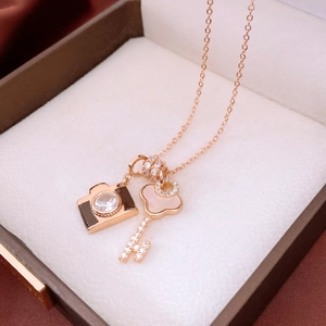 Macro detail of rose gold camera and key pendant necklace with zircon and shell inlay