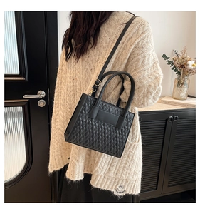 Detail of black quilted square handbag with gold hardware and adjustable strap
