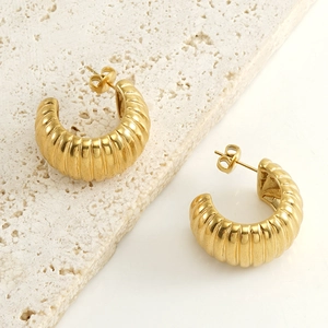 Boucles d'oreilles créoles dorées avec texture spirale sur pierre beige