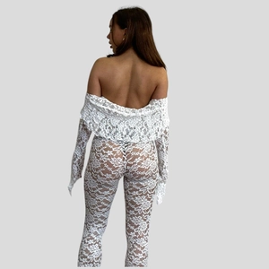 Detail of white lace two-piece set featuring off-shoulder top and sheer flare trousers