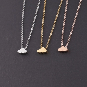 Three cloud pendant necklaces in silver, gold, and rose gold on a dark textured background