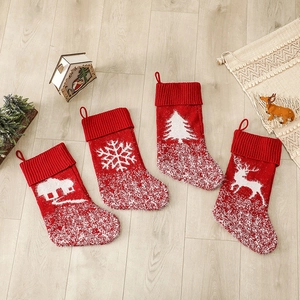 Set of 4 knitted Christmas stockings with reindeer and snowflake patterns on wooden floor