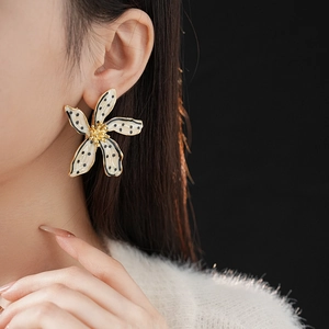 Detail of vintage flower earrings with black dots on cream enamel and gold core
